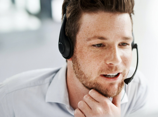 Junger Mann mit Headset telefoniert mit einem Kunden